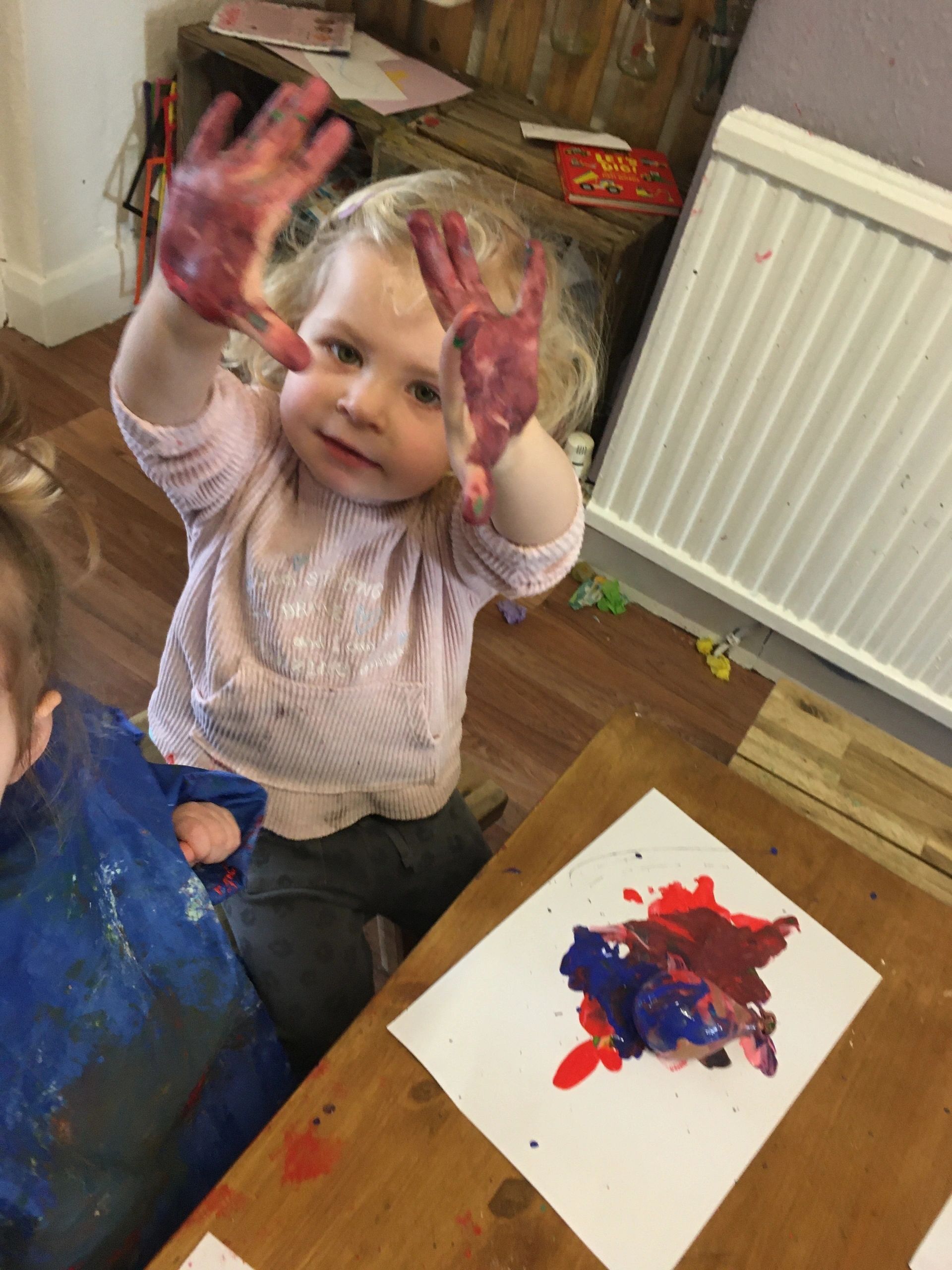 A toddler showing painted hands after an art activity